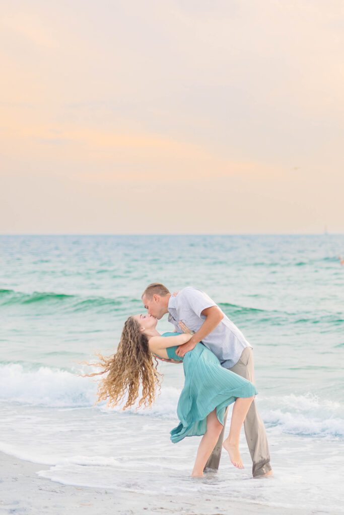 A romantic couple kiss on the beach of Sand Key Beach, feeling confident overcoming fear in their portraits.